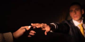 person in black long sleeve shirt holding hands with orange light