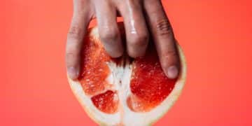 person holding red pomelo fruit