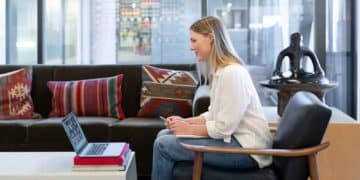 woman in white long sleeve shirt sitting on red and brown couch