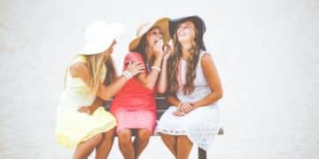 three women sitting on brown wooden bench