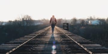 man walking in the middle of rail road